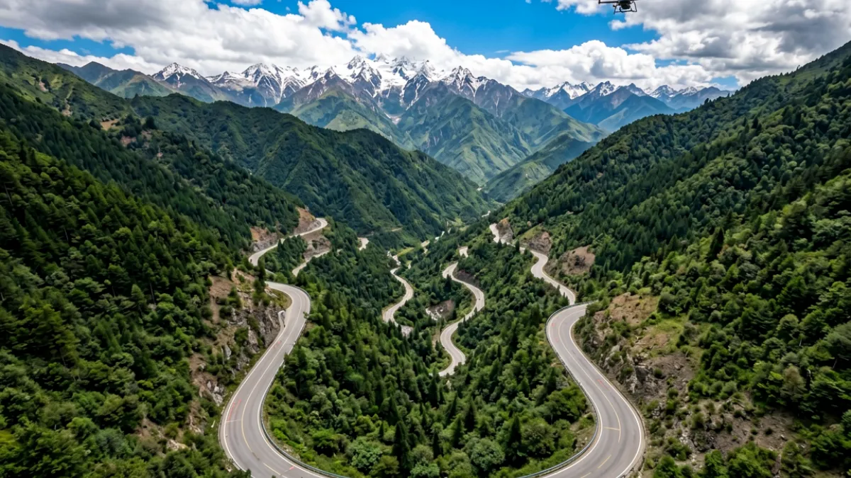 无人机航拍山间公路，蜿蜒道路两侧植被茂密，画面开阔震撼